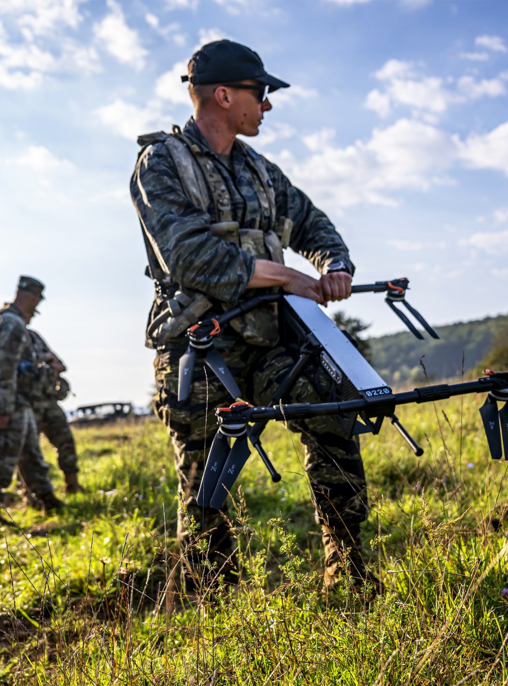 A soldier holding a drone in a field