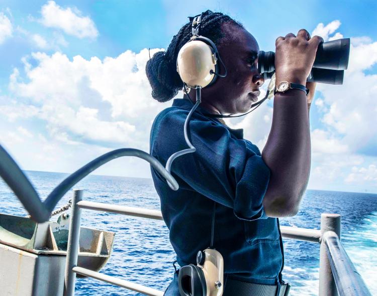 Navy officer on a ship looking through binoculars