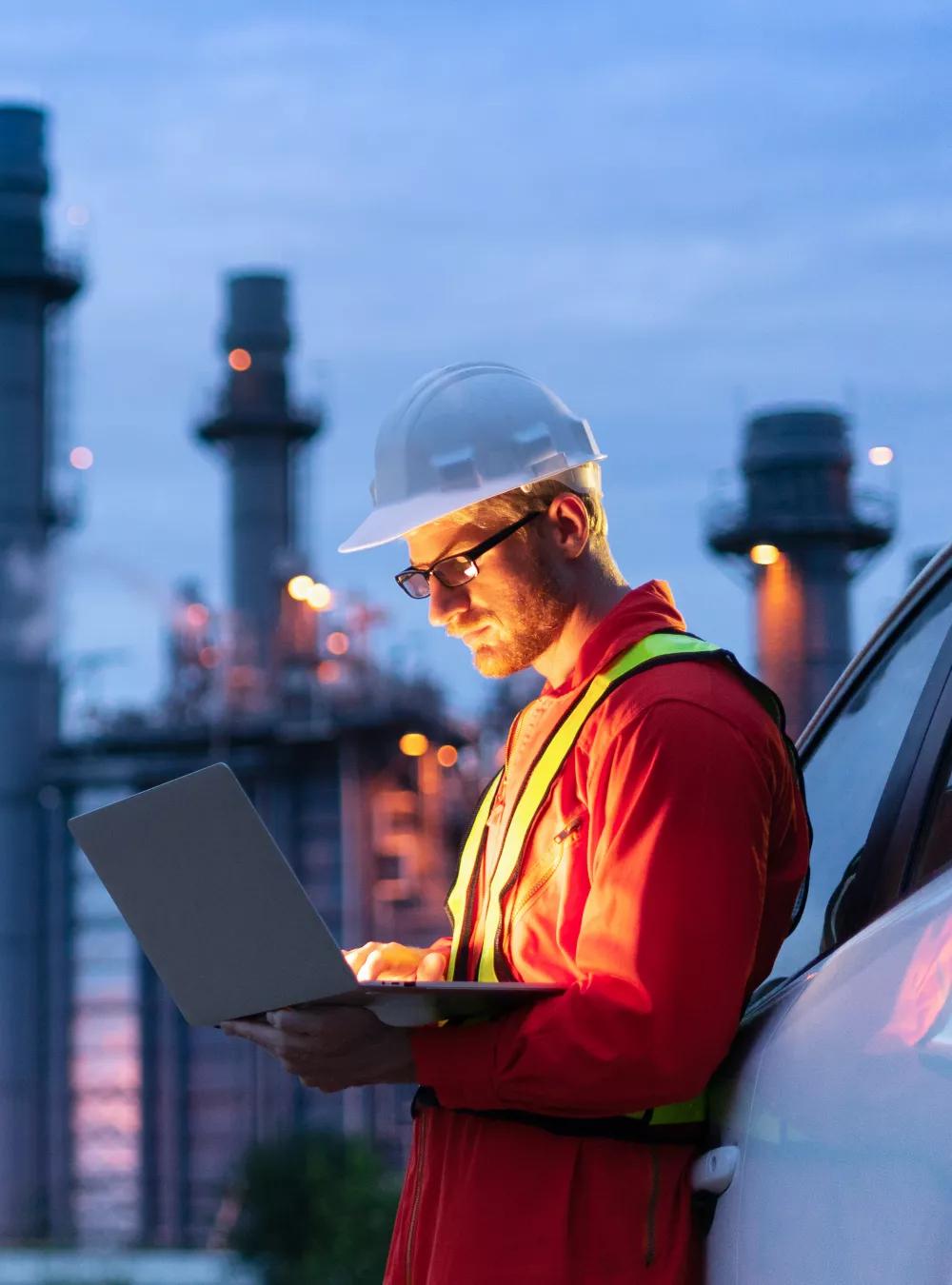 Engineer on a laptop at an oil refinery