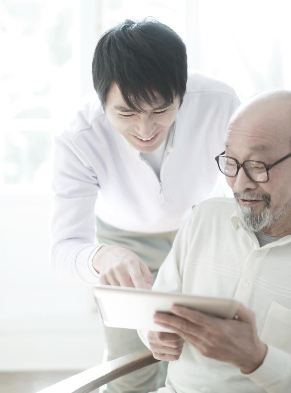 Father and his adult son looking at a tablet screen