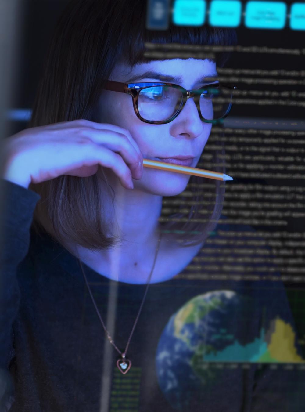 Woman in glasses analyzes data in a dark room