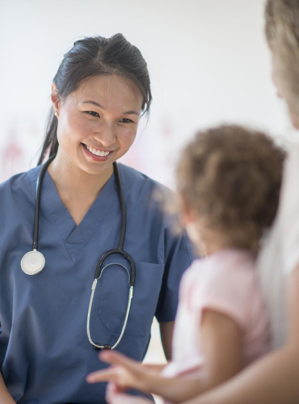 Clinician smiling at a pediatric patient who is accompanied by a caregiver