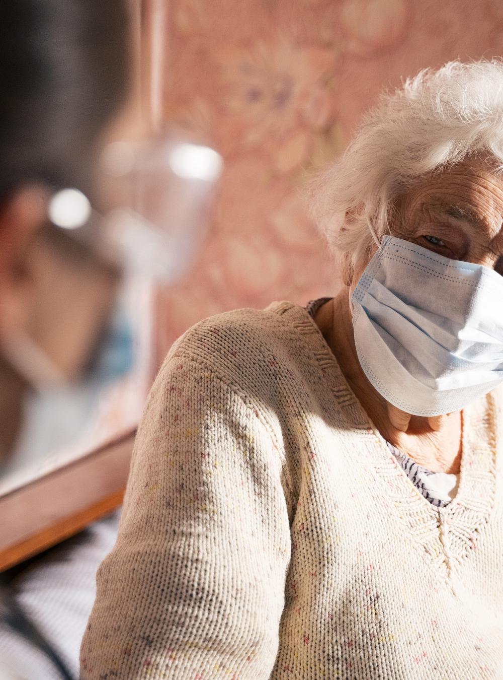 Doctor and elderly nursing home patient, both wearing masks
