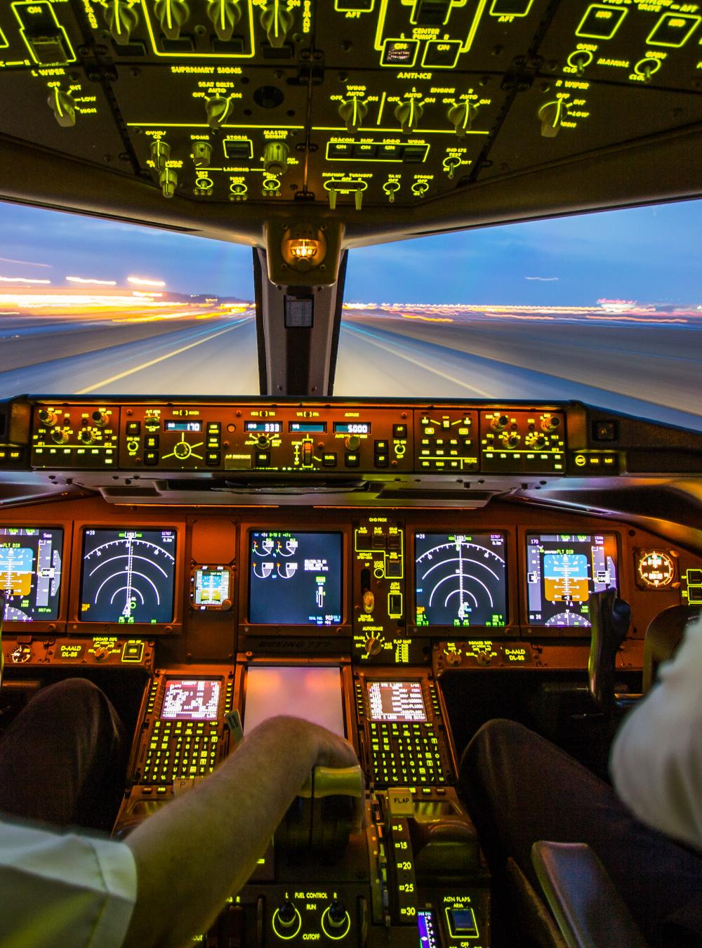 Two pilots in a lit up cockpit of an aircraft about to take off