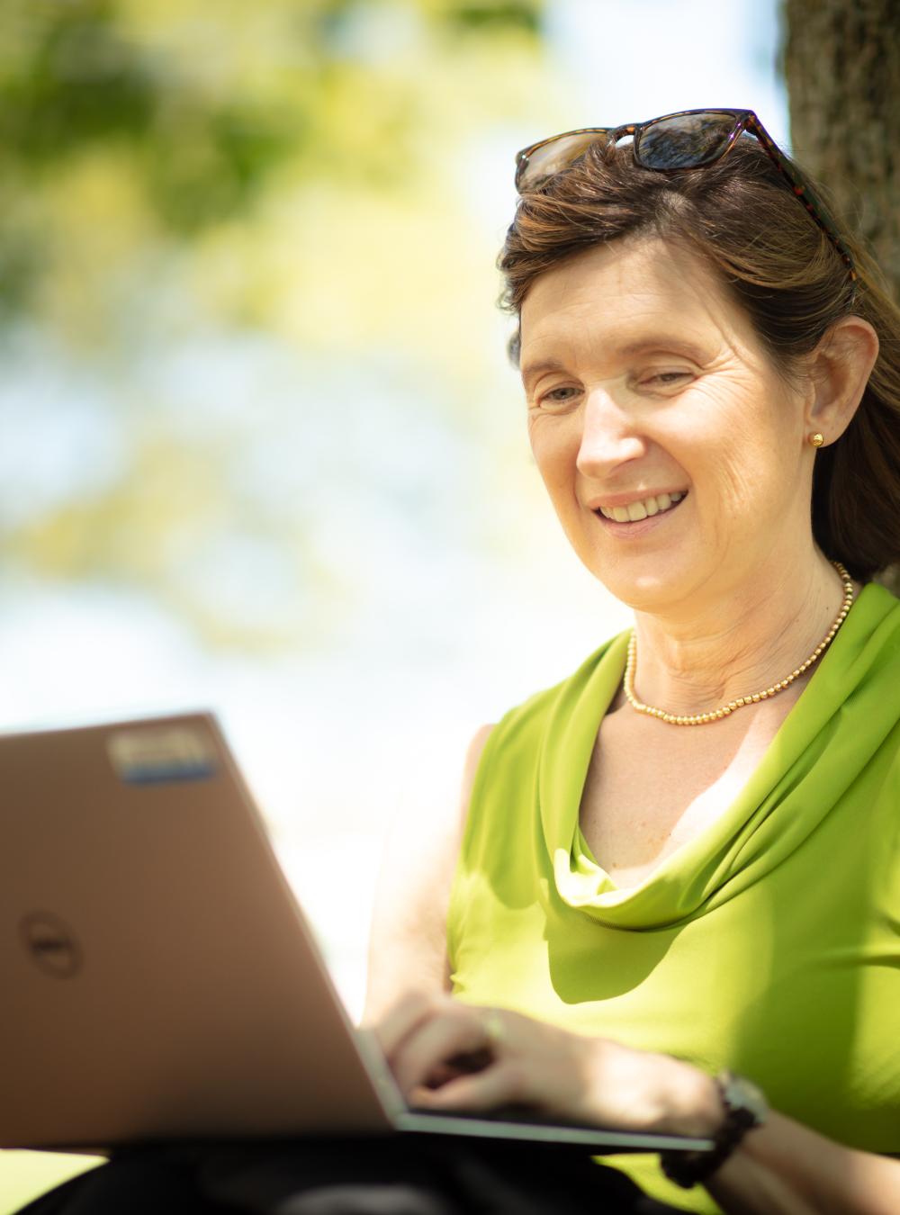 Cindy Dominguez working on her laptop while outdoors