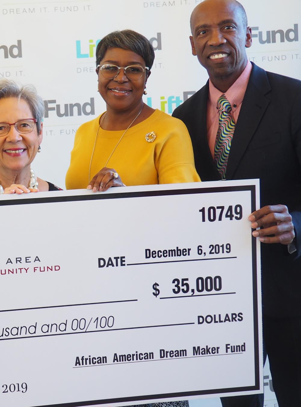 Members of LiftFund smiling and holding a large check for $35,000