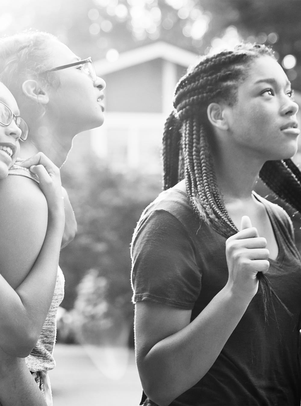 Teenage girl embracing friend while hanging out in neighborhood