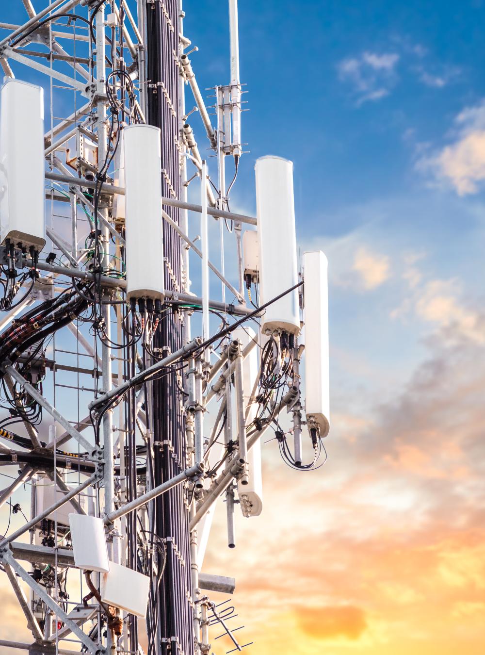 5G towers against a blue and yellow cloudy sky