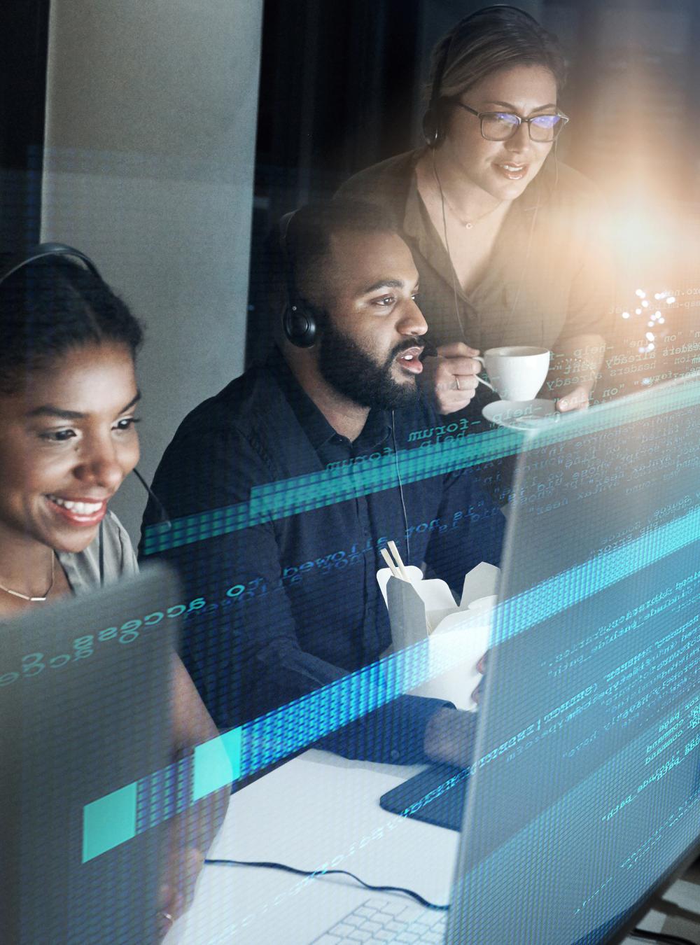 Three coworkers working together at a computer screen