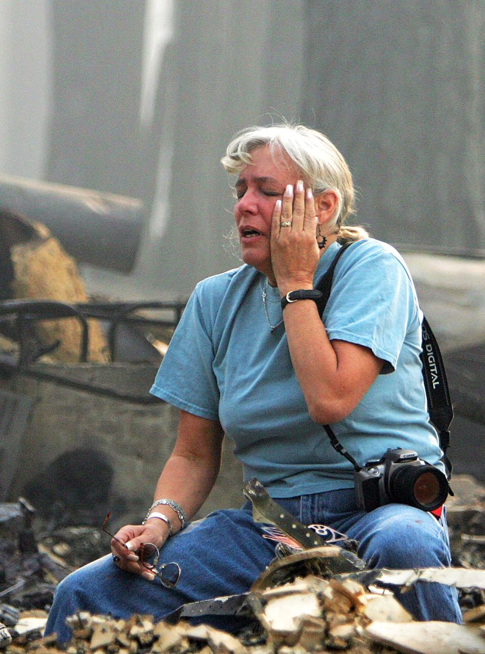 A woman cries as she sits in the remains of a home that was completely destroyed by fire
