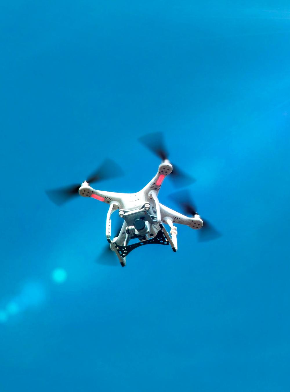 A drone with camera flying against a blue sky