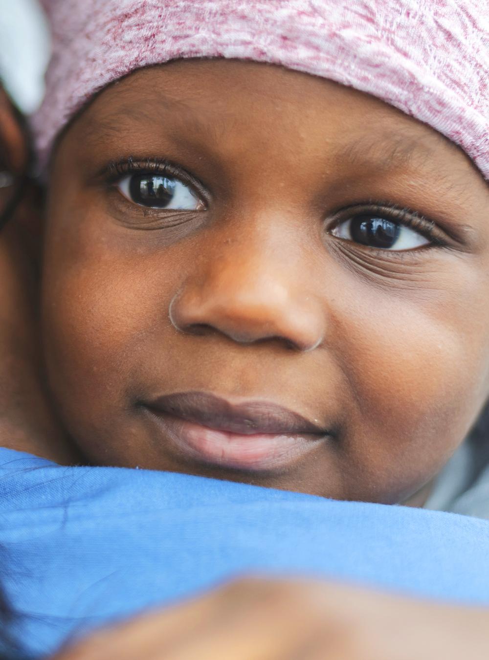 Child with cancer hugging caretaker