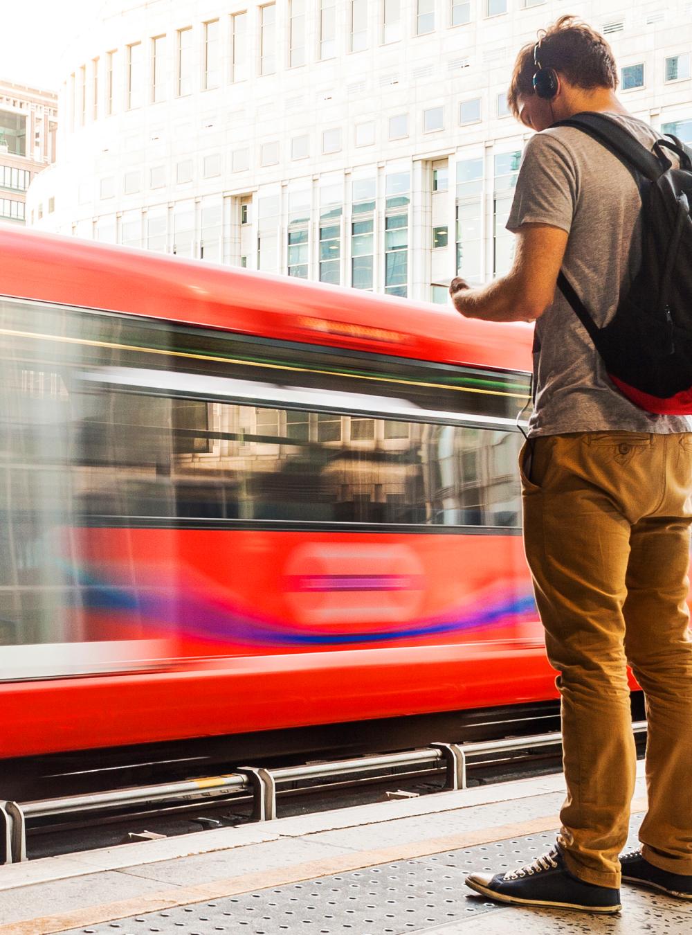 Young man with backpack and headphones waiting for a train