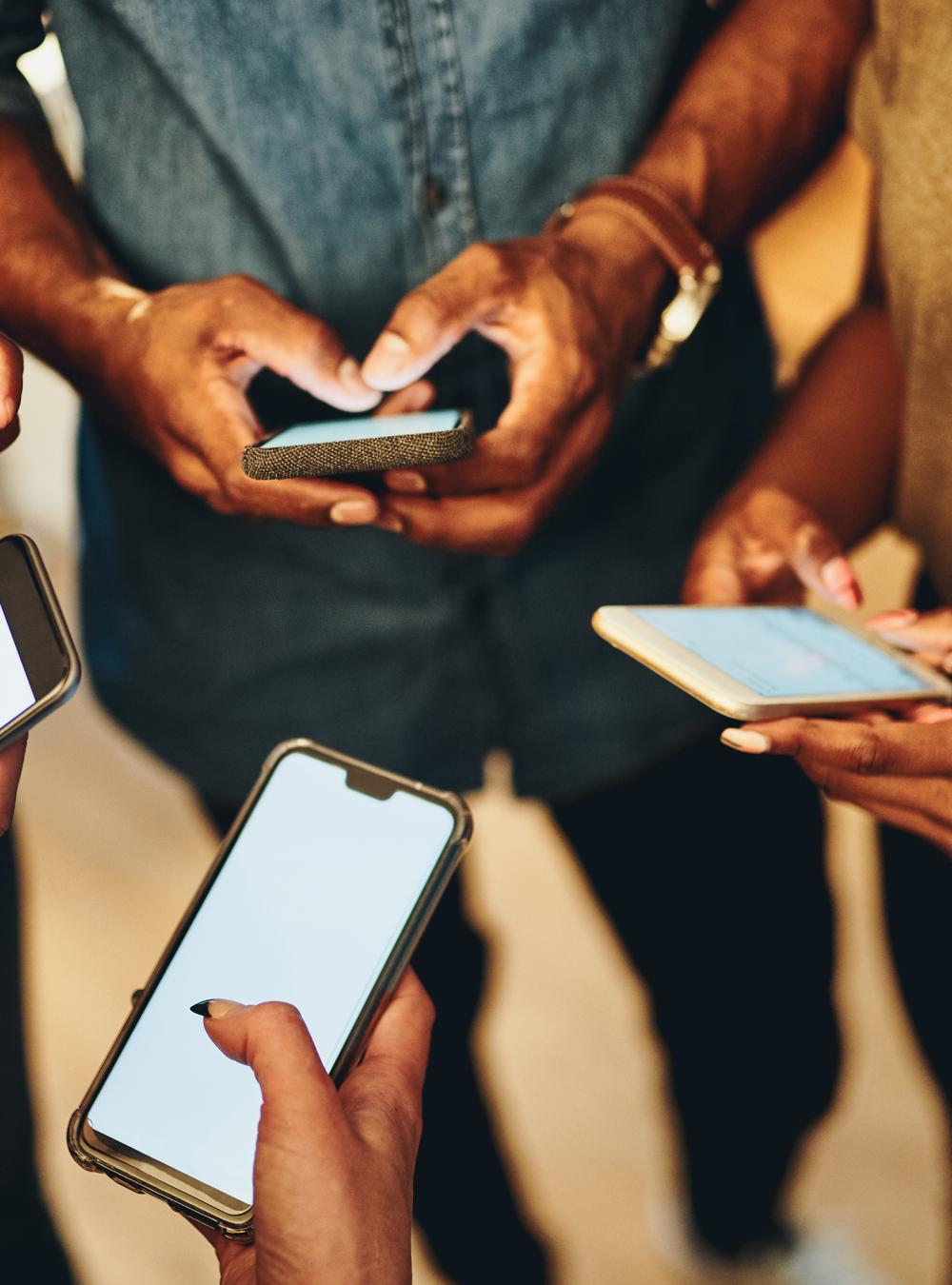 Group of people standing in a circle while everyone is using their smartphone