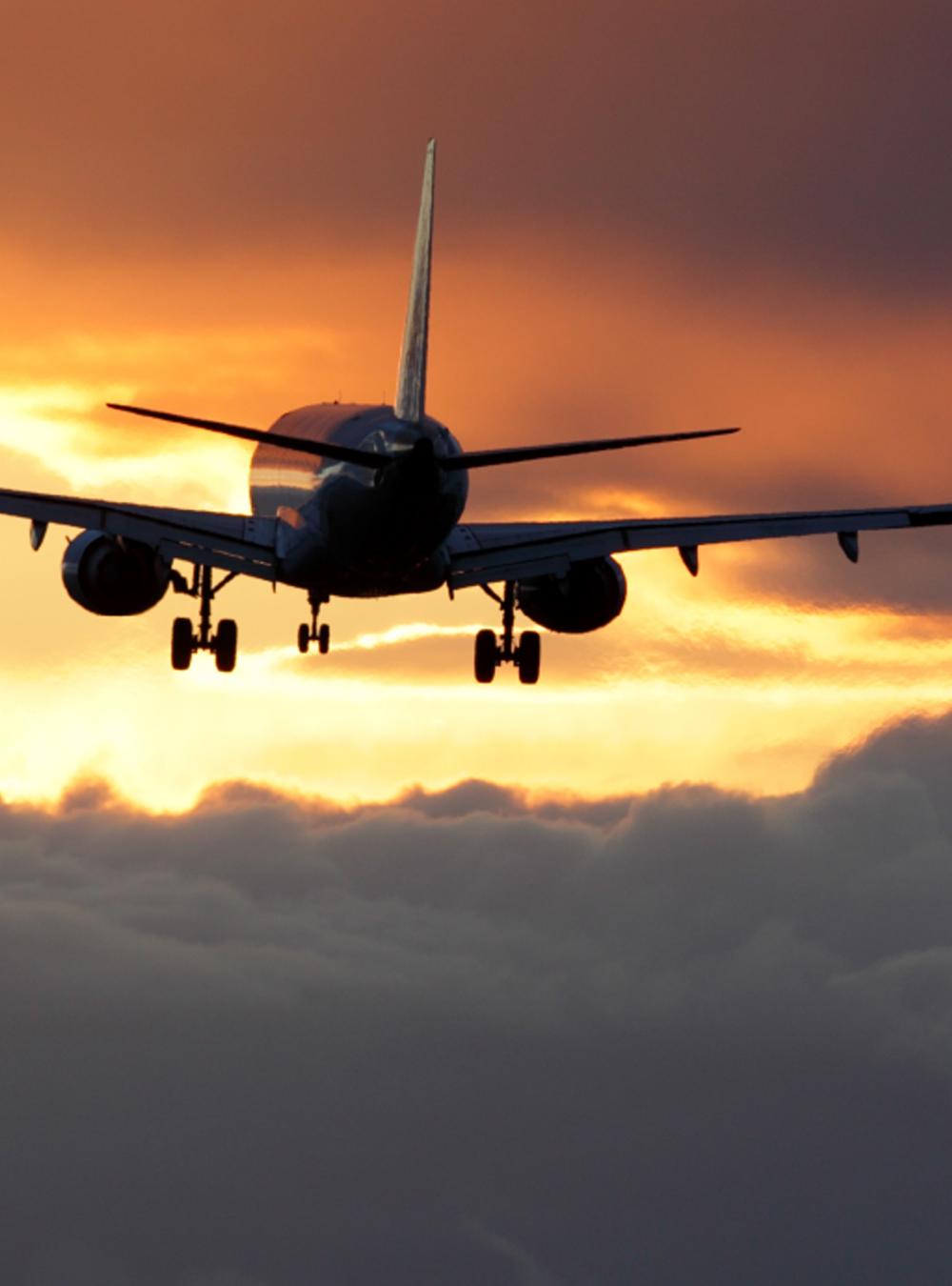 Plane taking off into clouds and sunset