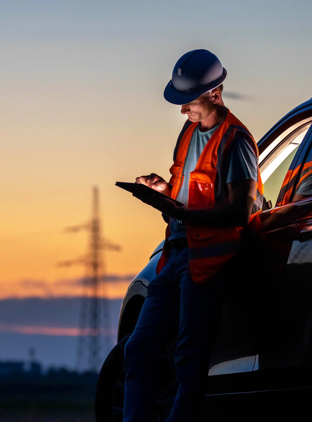 Engineer working on a laptop near high voltage poles