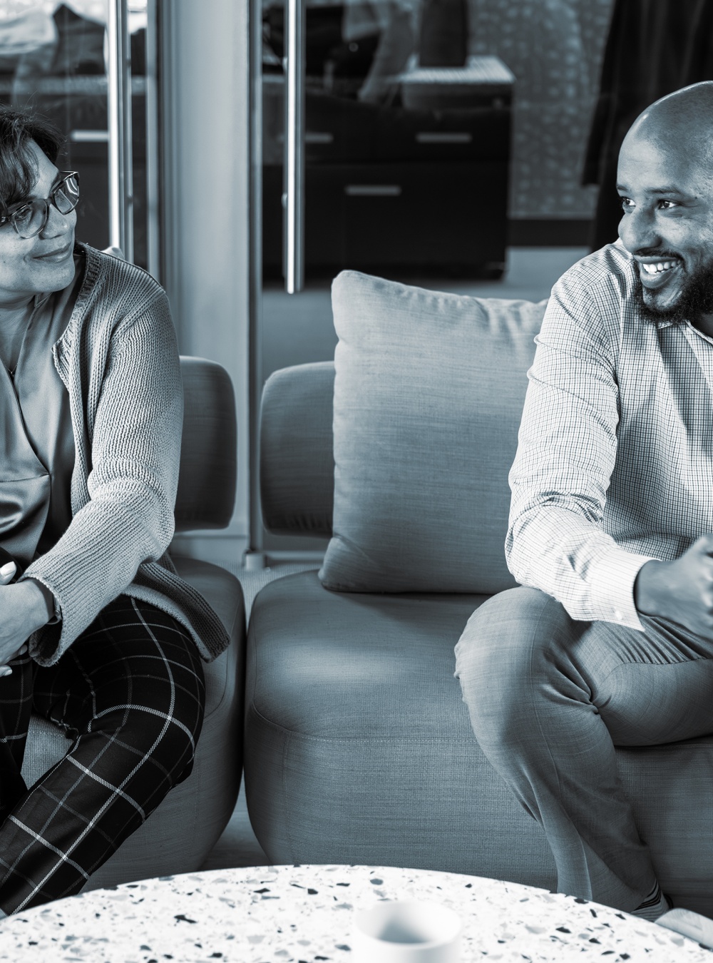 Two employees sitting on a couch having a conversation