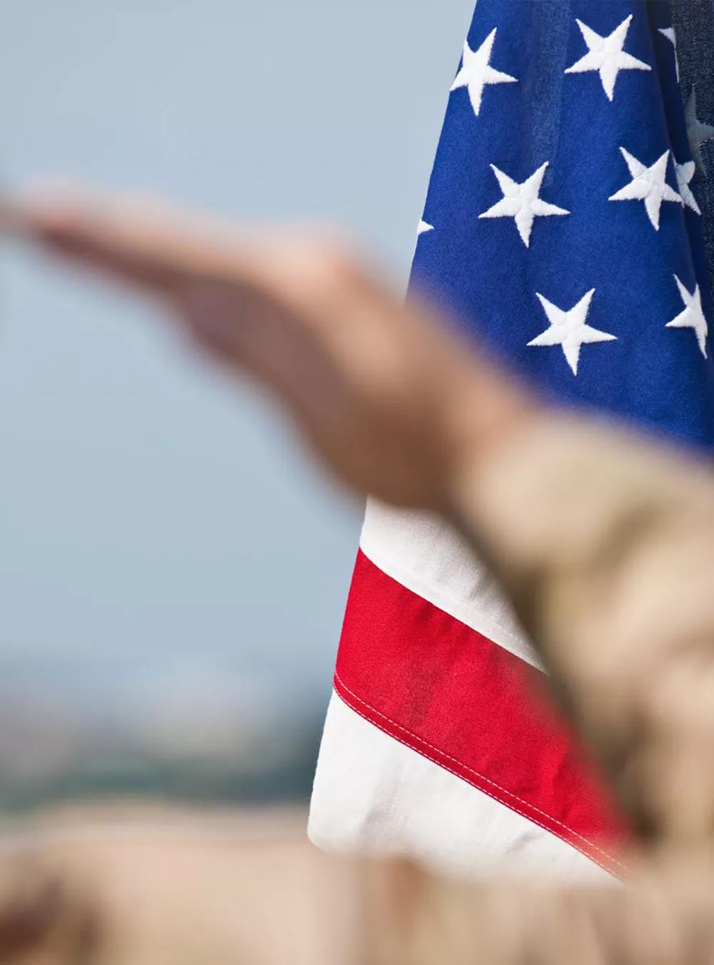Military person saluting US flag