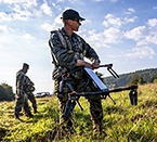 A soldier holding a drone in a field
