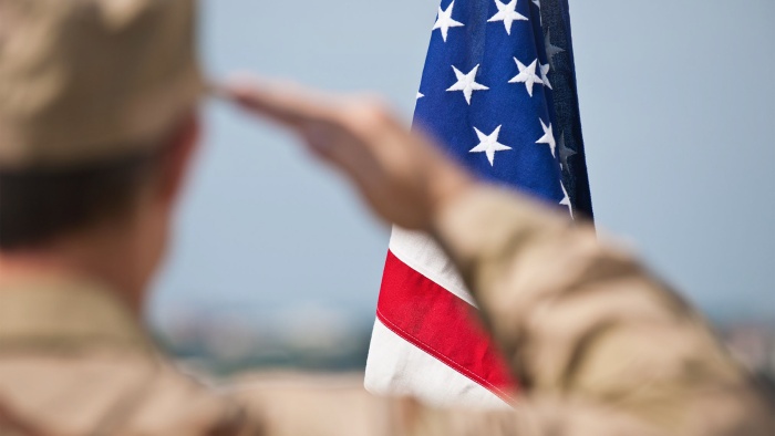 Military person saluting US flag