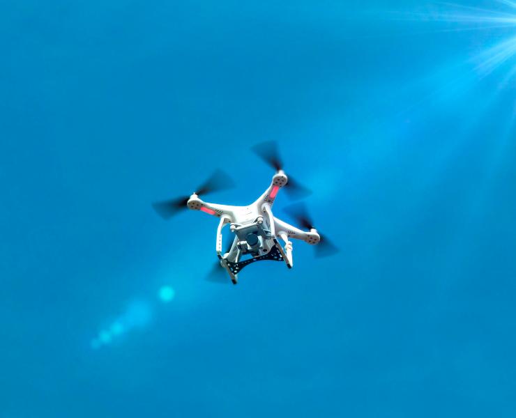 A drone with camera flying against a blue sky
