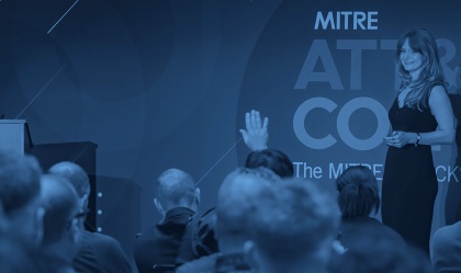 A group of people in a conference room listening to a speaker at the ATT&CKcon cybersecurity conference