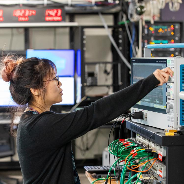 Employee operating an oscilloscope in a lab