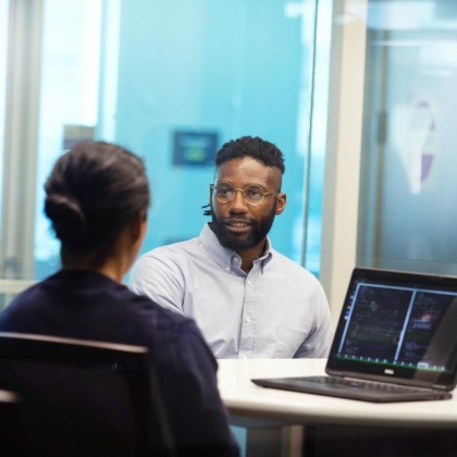 Two employees at a desk talking to each other